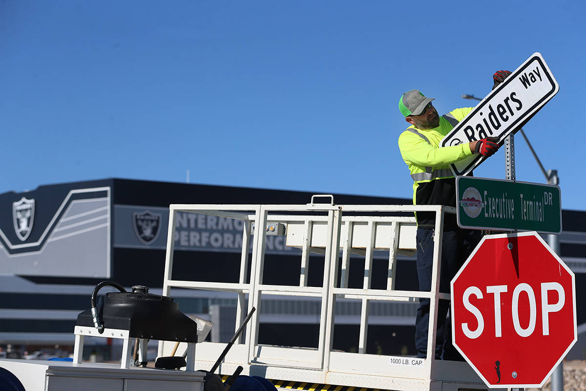 Kevin Weakland, signs and margins technician for the city of Henderson, installs a Raiders Way ...