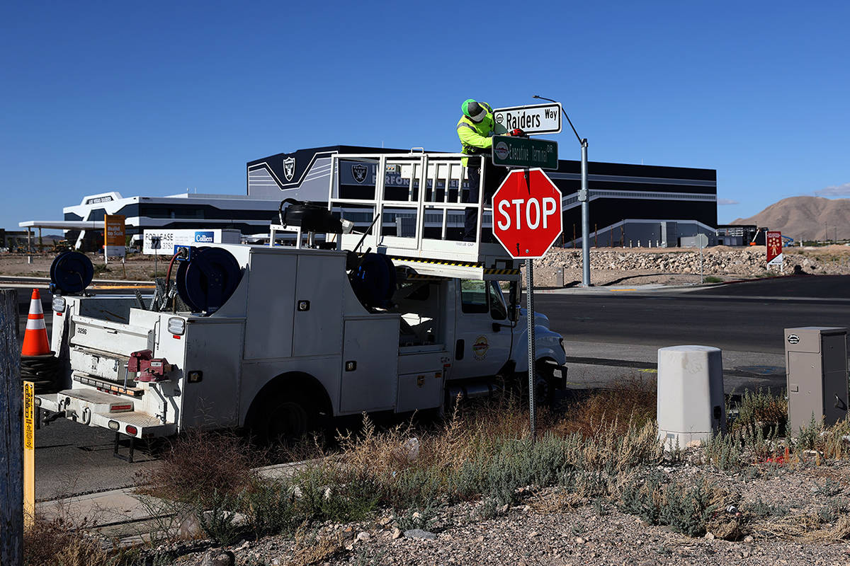 Kevin Weakland, signs and margins technician for the city of Henderson, installs a Raiders Way ...