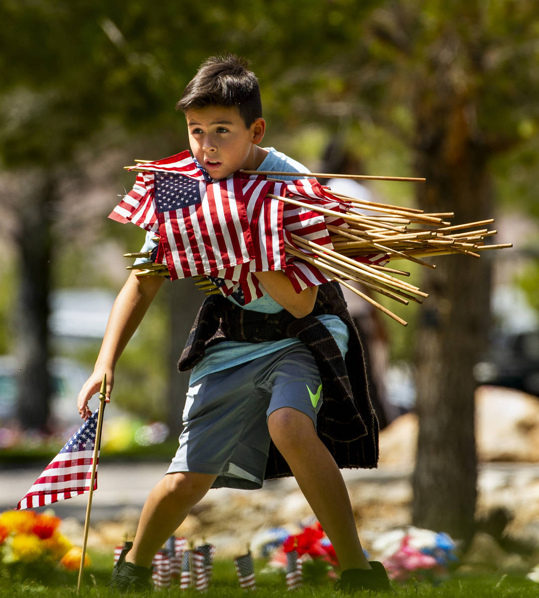 Baron Petersen, 10, helps to gather flags following a Memorial Day ceremony at the Southern Nev ...