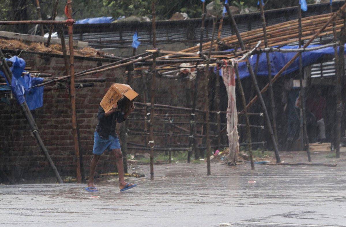 A man covers him head with a box and walks in the rain ahead of Cyclone Amphan landfall, at Bha ...