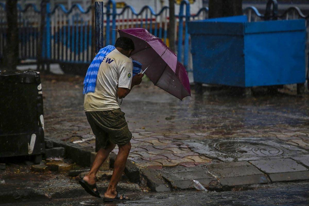 A man struggles to hold his umbrella and walk against high wind in Kolkata, India, Wednesday, M ...