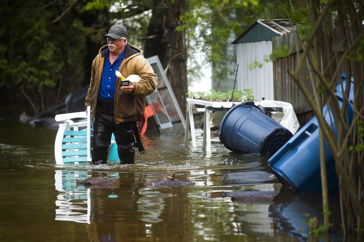 Mark Musselman brings a chair to the front of his house from the back yard, wading through floo ...