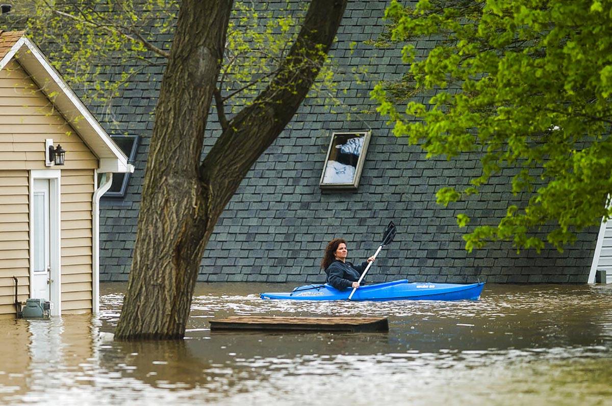 People use kayaks to assess the damage at homes in their neighborhood on Oakridge Road on Wixom ...