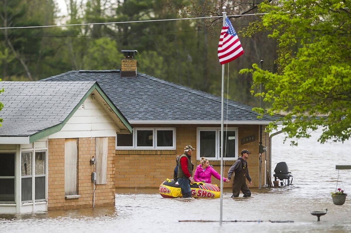 People help each other travel from one home to another using an inflatable raft on Oakridge Roa ...