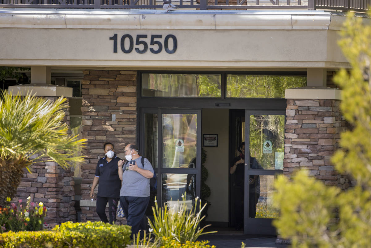 Two people walk out of The Heights of Summerlin which has had numerous deaths there due to Covi ...