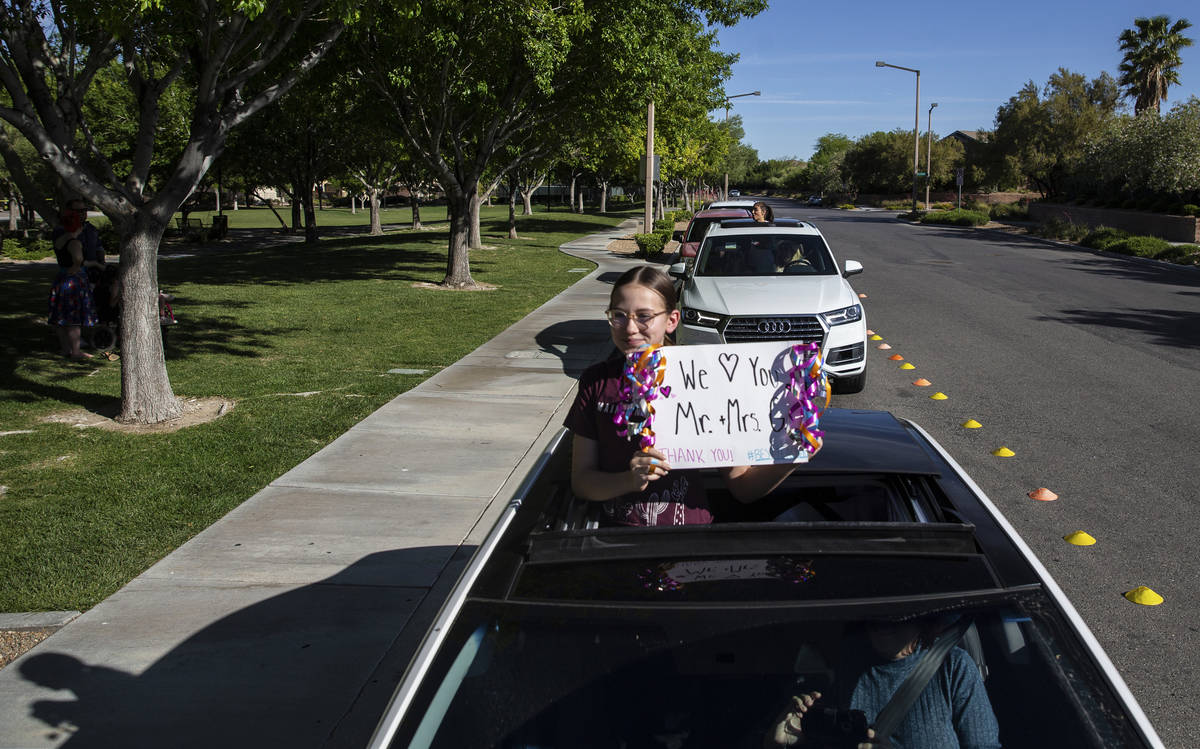 Children hold signs in a line of cars sending well wishes to Gary Grosenick and wife Laurie, bo ...