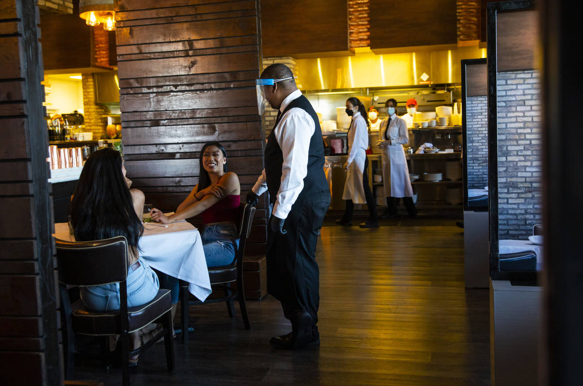 Diners Jasmin Montanez, left, and Juliana Asa talk with server Donald Bailey, wearing a face sh ...
