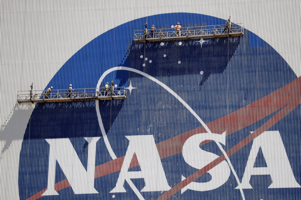 Workers near the top of the 526 ft. Vehicle Assembly Building at the Kennedy Space Center spruc ...