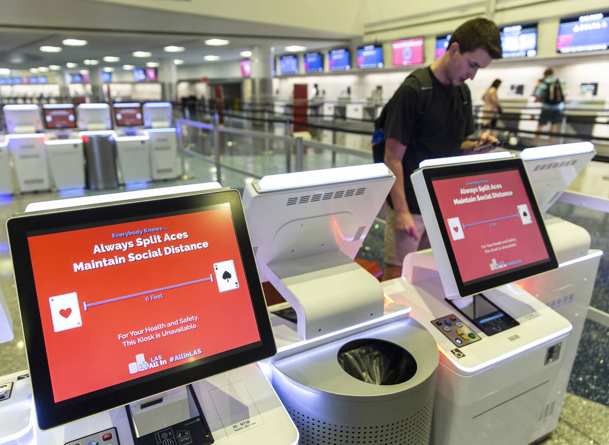 Travelers check in at newly arranged kiosks encouraging social distancing and outlining coronav ...