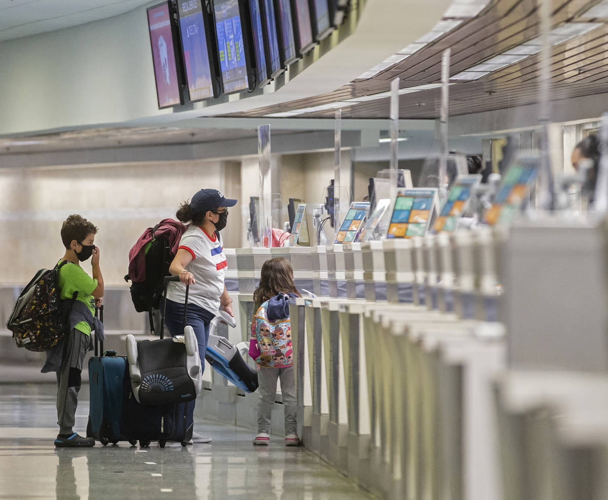 Travelers wearing medical masks check in at Delta Airlines in terminal one at McCarran Internat ...