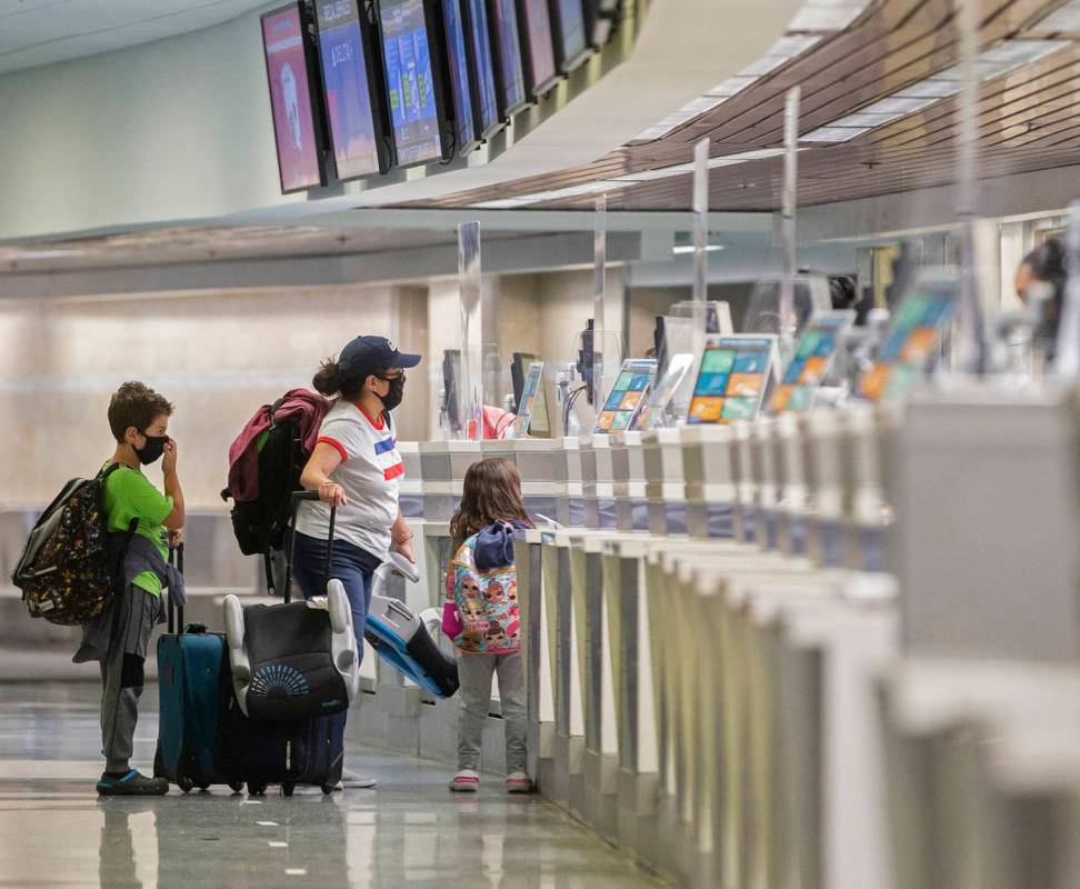 Travelers wearing medical masks check in at Delta Airlines in terminal one at McCarran Internat ...