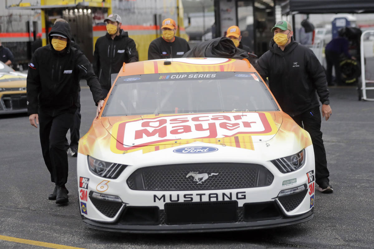 Crew members push the car of driver Ryan Newman as they wear masks as required for safety measu ...