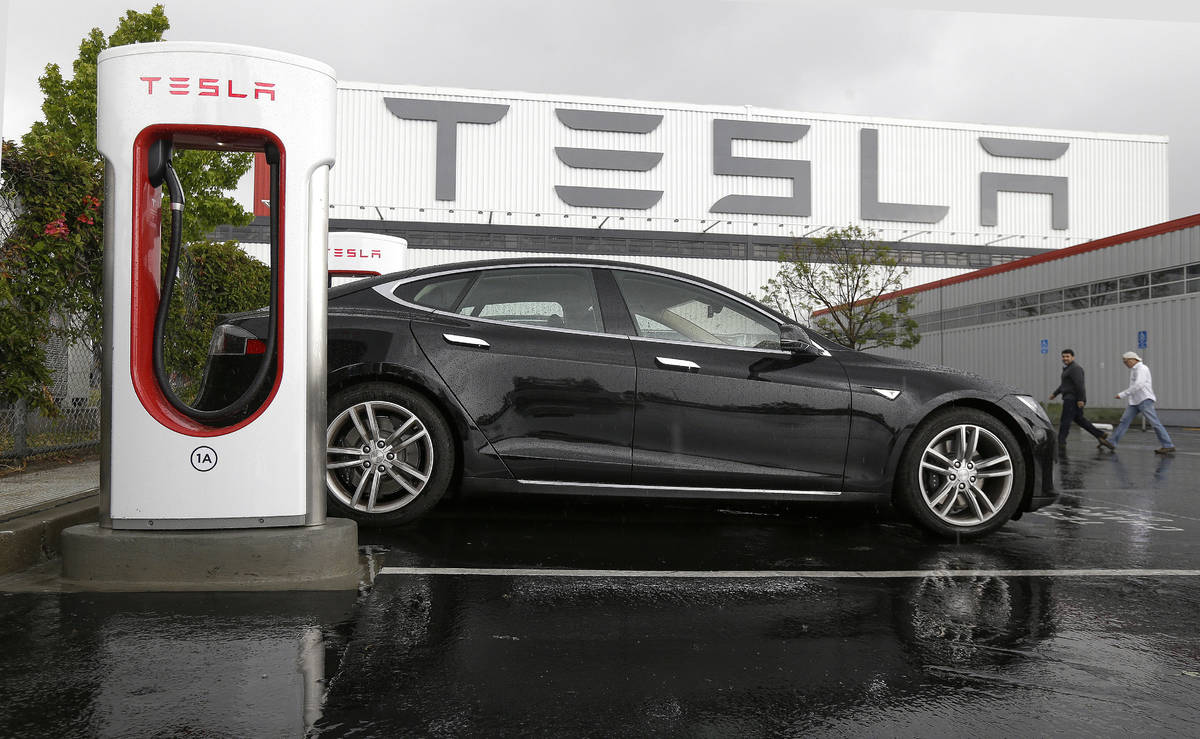 FILE - In this May 14, 2015, file photo, a Tesla vehicle is connected to a Tesla charging stati ...