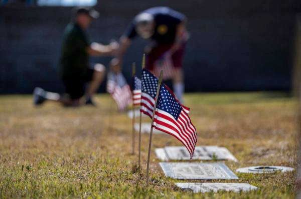 Frank Friedlander, left, and father Mort team up to plant more American flags on veteran's grav ...