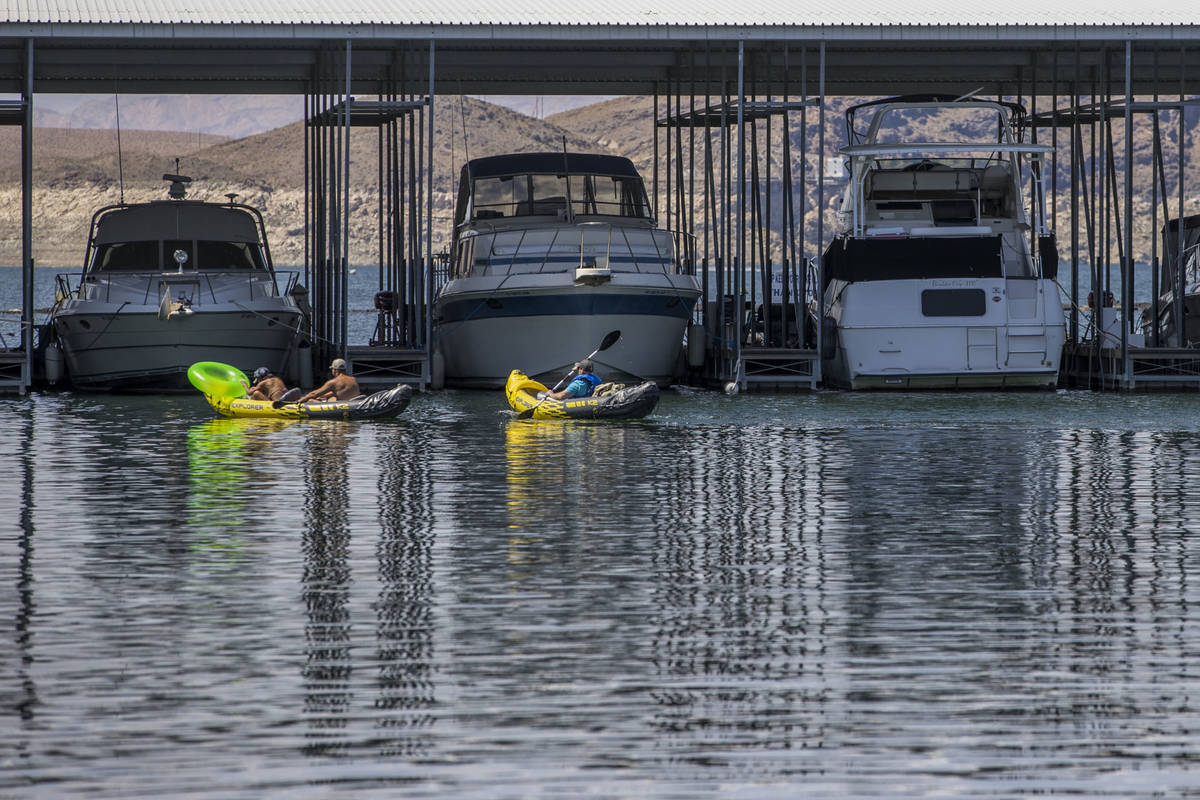 Kayakers move past moored boats at the Las Vegas Boat Harbor in the Lake Mead National Recreati ...