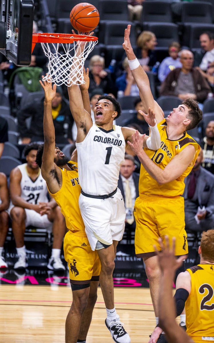 Colorado guard Tyler Bey (1, center) elevates for a shot between Wyoming forward Trevon Taylor ...