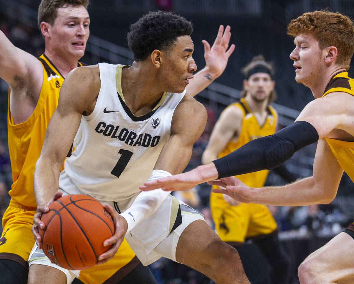 Colorado guard Tyler Bey (1, center) looks for a pass away from Wyoming guard Kenny Foster (22, ...