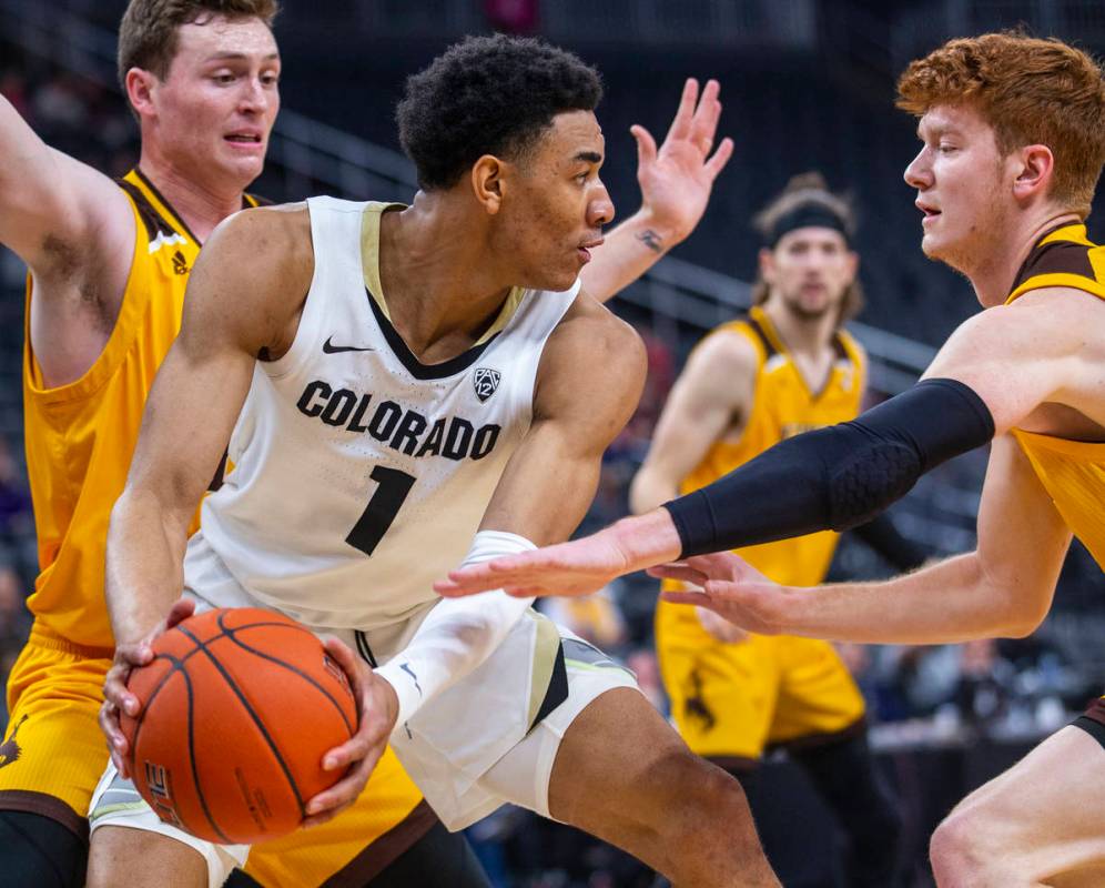 Colorado guard Tyler Bey (1, center) looks for a pass away from Wyoming guard Kenny Foster (22, ...