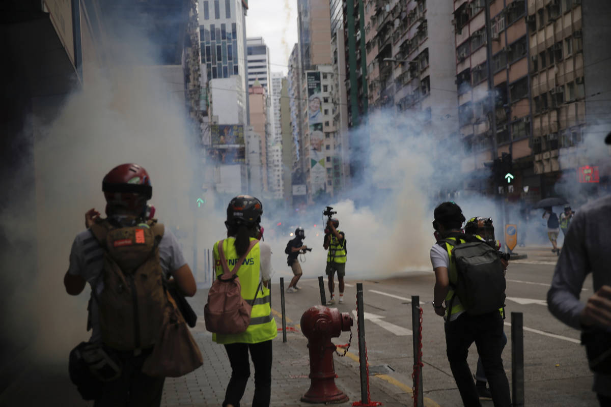 Members of the media take cover as police fire tear gas during a protest against Beijing's nati ...