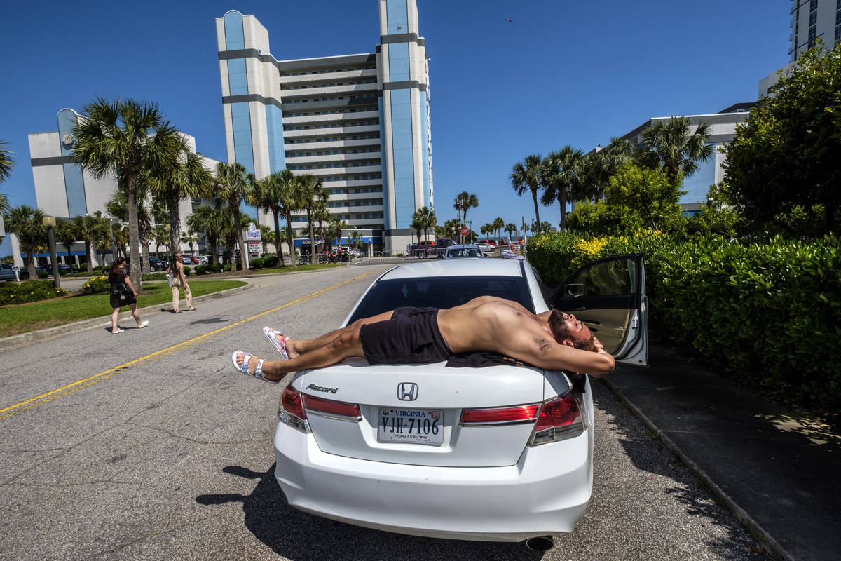 Darien Foxx, of Virginia, sun bathes on the back of his car while he waits on the rest of his p ...