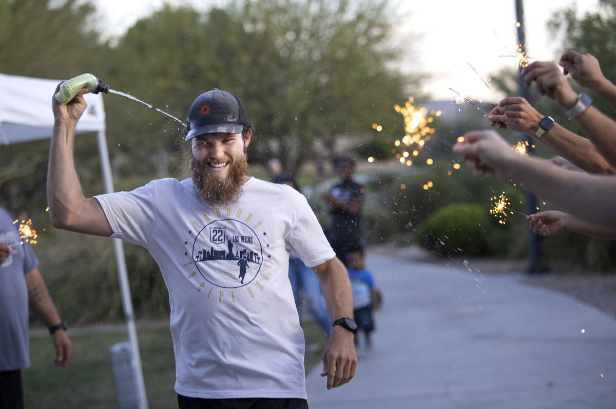 Peter Makredes cools off as his friends and family hold sparklers to encourage him as he runs f ...