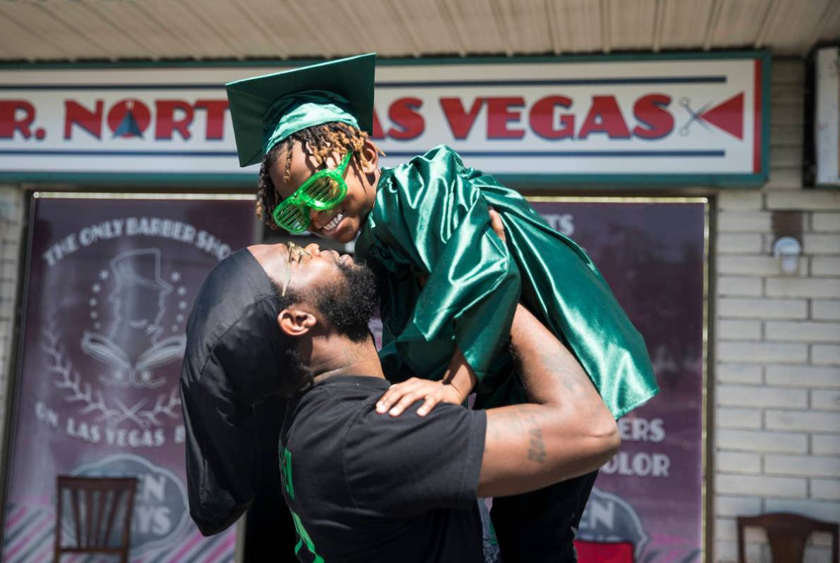Morgan Harris holds up his son Messiah Harris, 6, after having his kindergarten graduation phot ...