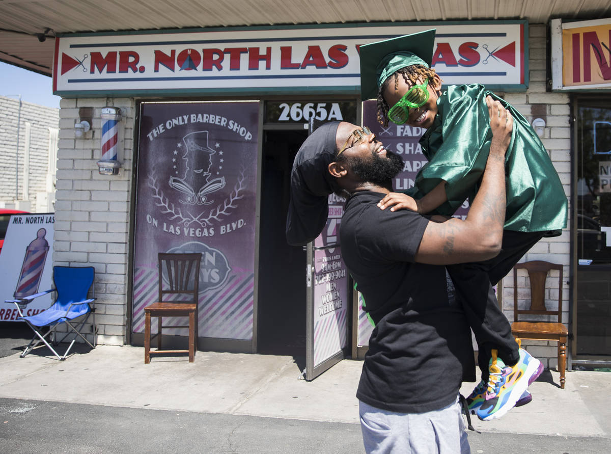 Morgan Harris holds up his son Messiah Harris, 6, after having his kindergarten graduation phot ...