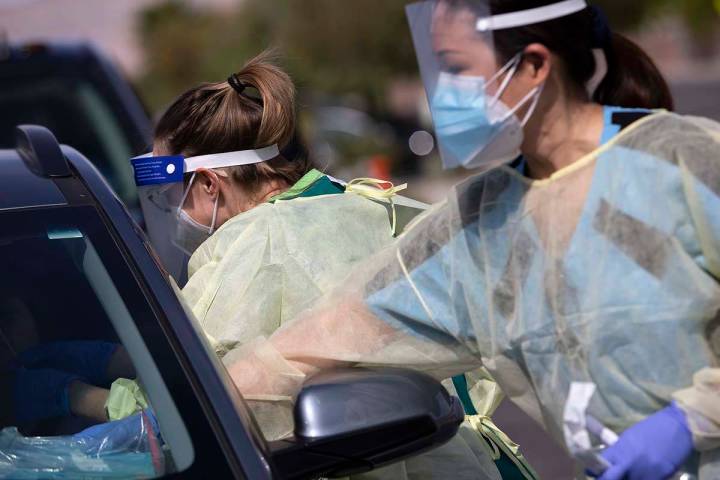 A volunteer swabs a patient's nose at a COVID-19 testing site at Calvary Chapel Las Vegas, May ...