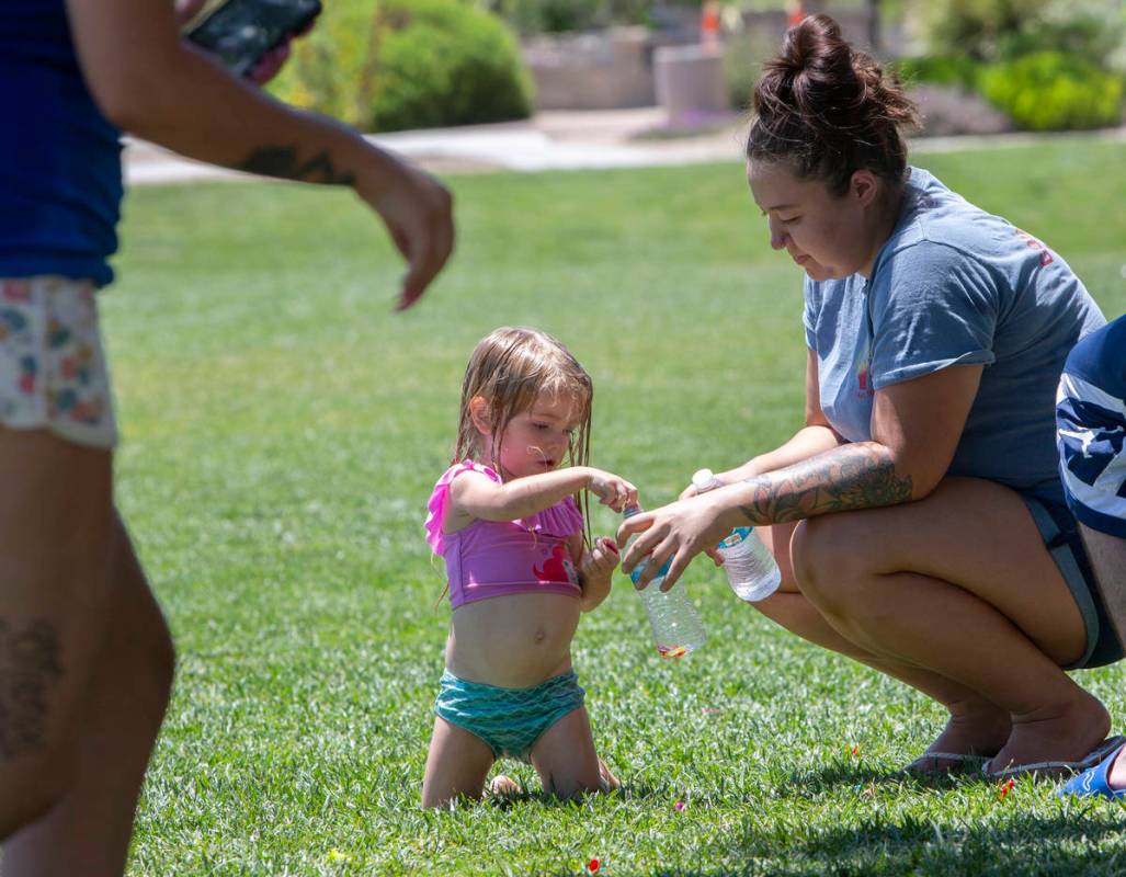 Aaliyah Merrick, 3, picks up balloon pieces with Julianne Tuttle after a water balloon fight at ...