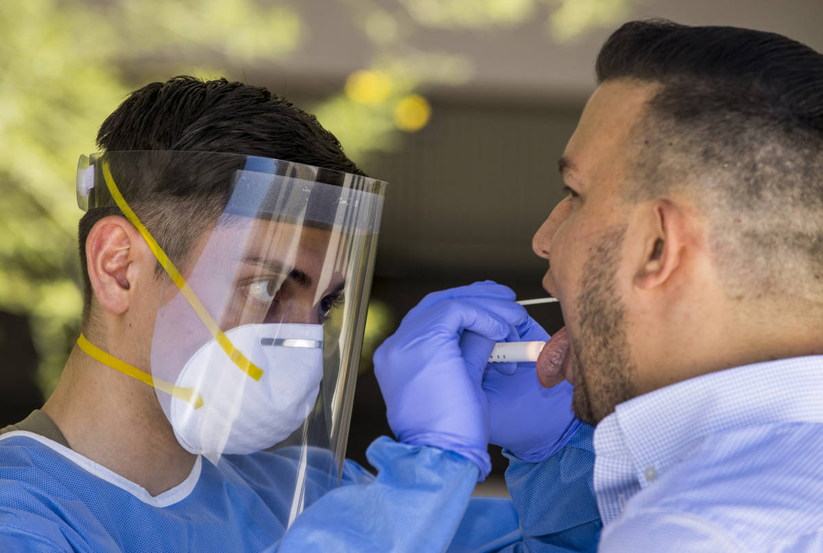 Nevada National Guard soldier Pfc. Nikolas Herrera, left, inserts a swab into the mouth of Paul ...