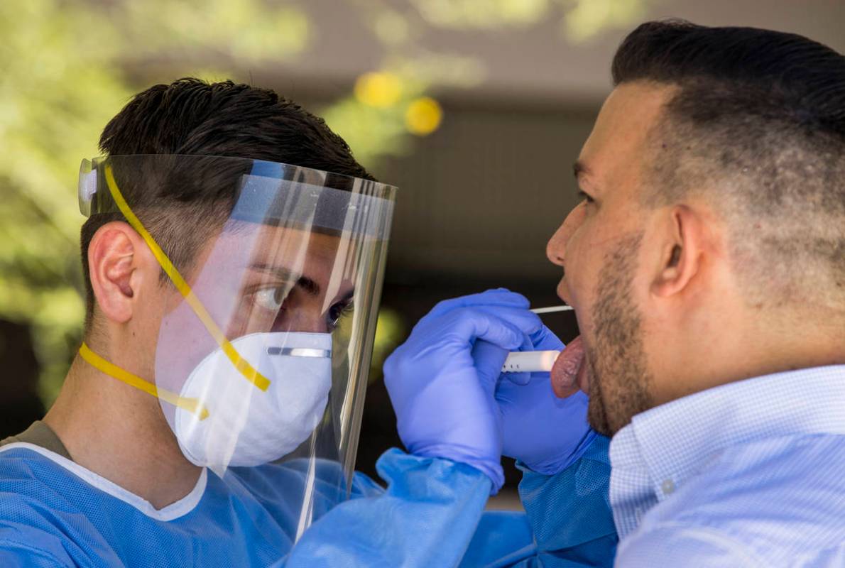 Nevada National Guard soldier Pfc. Nikolas Herrera, left, inserts a swab into the mouth of Paul ...