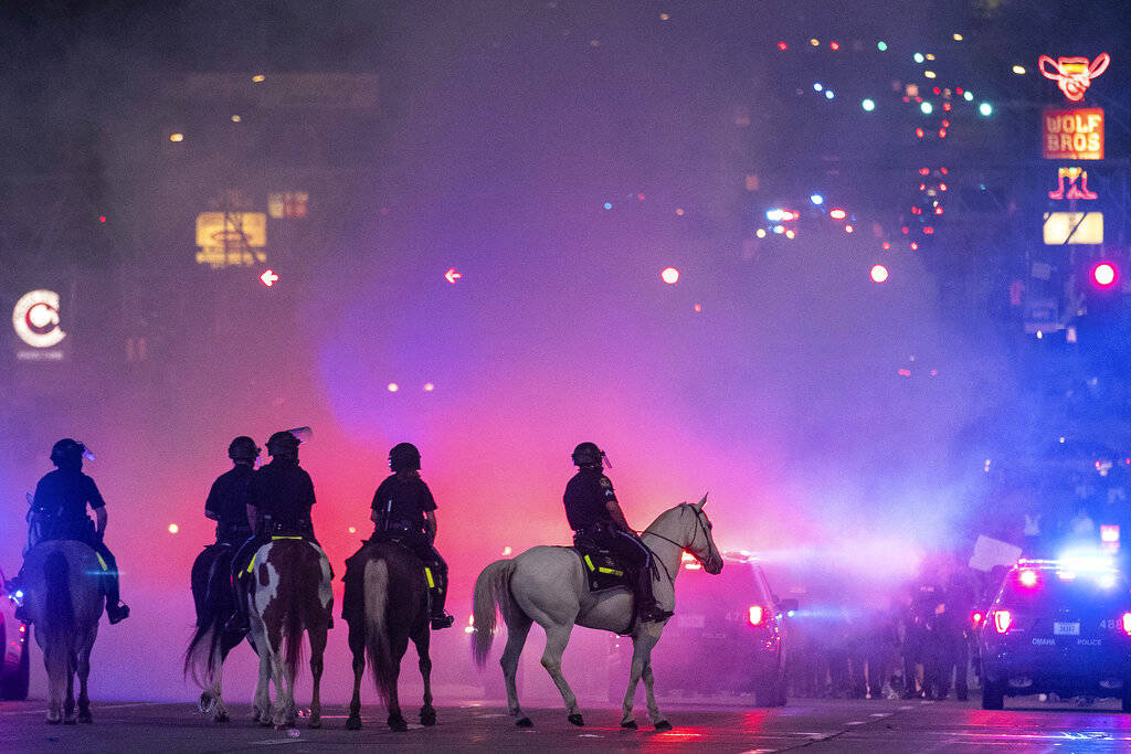 The Omaha police mounted patrol are silhouetted in tear gas as they approach protesters at 72nd ...