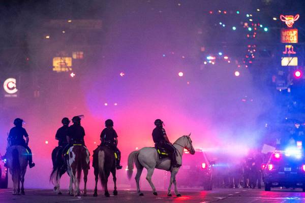 The Omaha police mounted patrol are silhouetted in tear gas as they approach protesters at 72nd ...