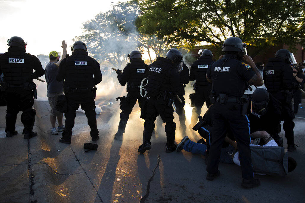 Police hold a man on the ground as tear gas is deployed and protesters rally near 72nd and Dodg ...