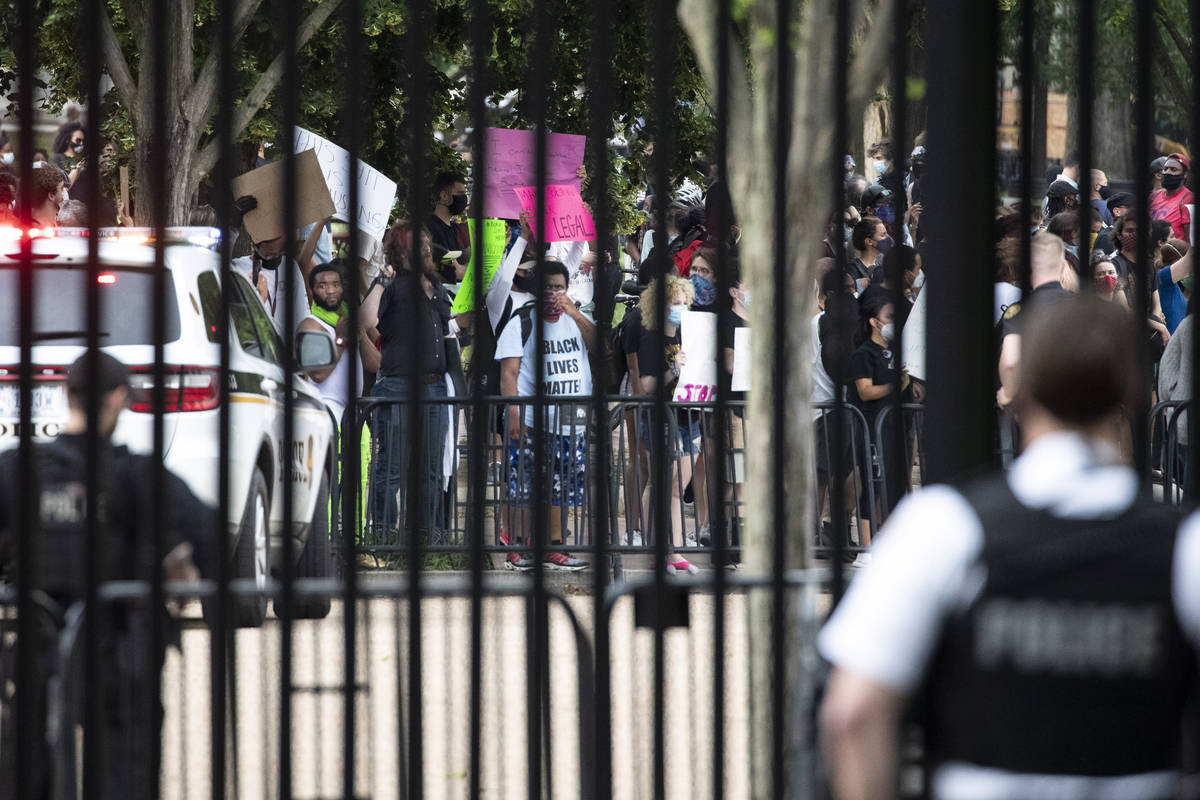 A U.S. Secret Service officer stands inside the fence at the White House as demonstrators prote ...