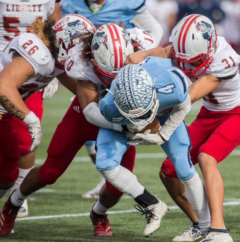 Centennial senior Aaron Johnson (4) is wrapped up in the backfield by Liberty sophomore linebac ...
