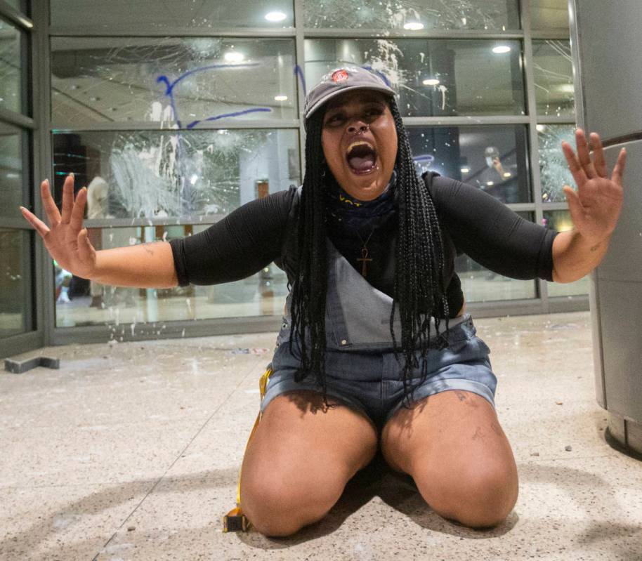 A woman pleads for protesters to stop breaking windows at an office building on South Las Vegas ...