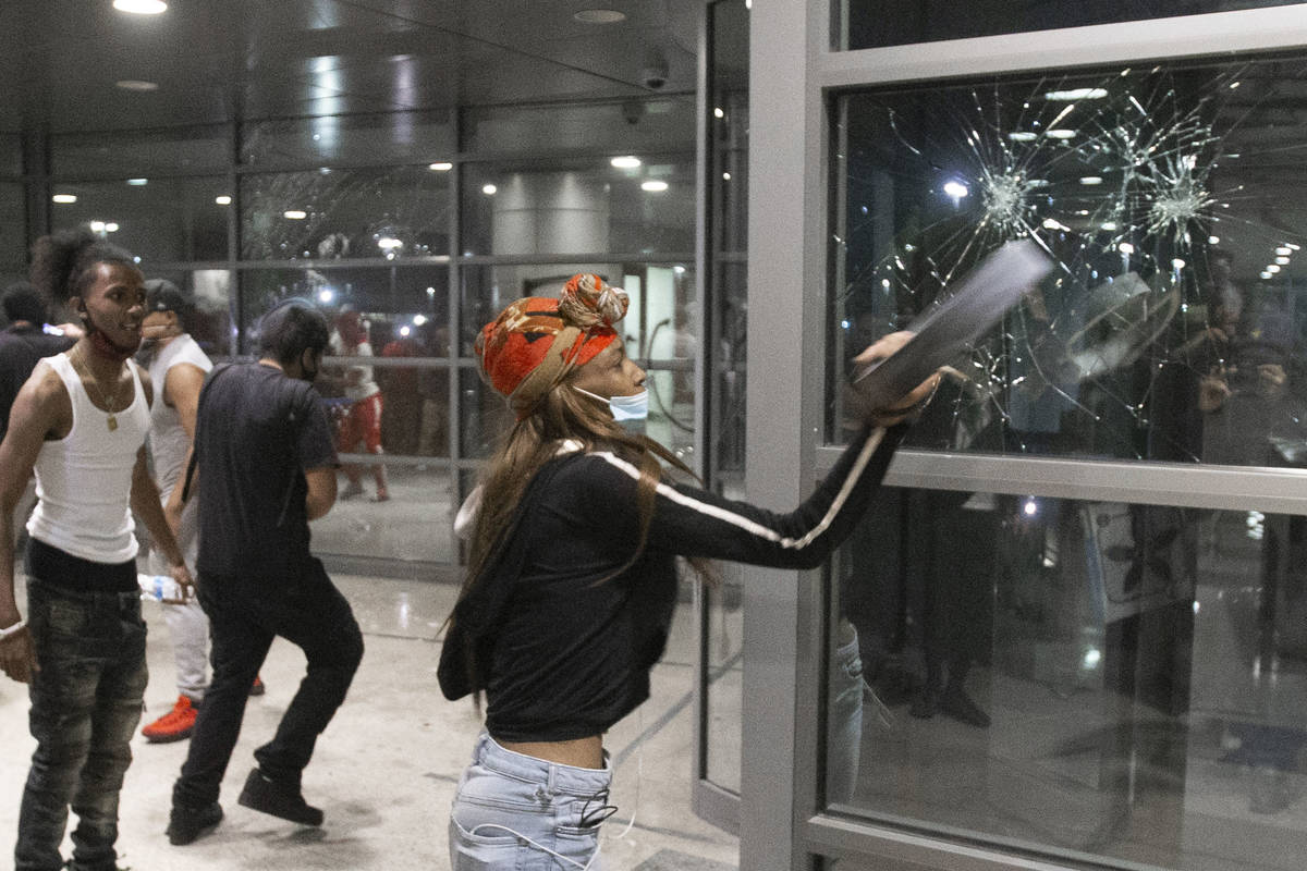 A protester smashes the window of an office building on South Las Vegas Boulevard in downtown L ...