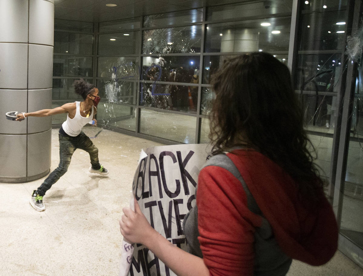 A protester throws a metal object at the window of an office building on South Las Vegas Boulev ...