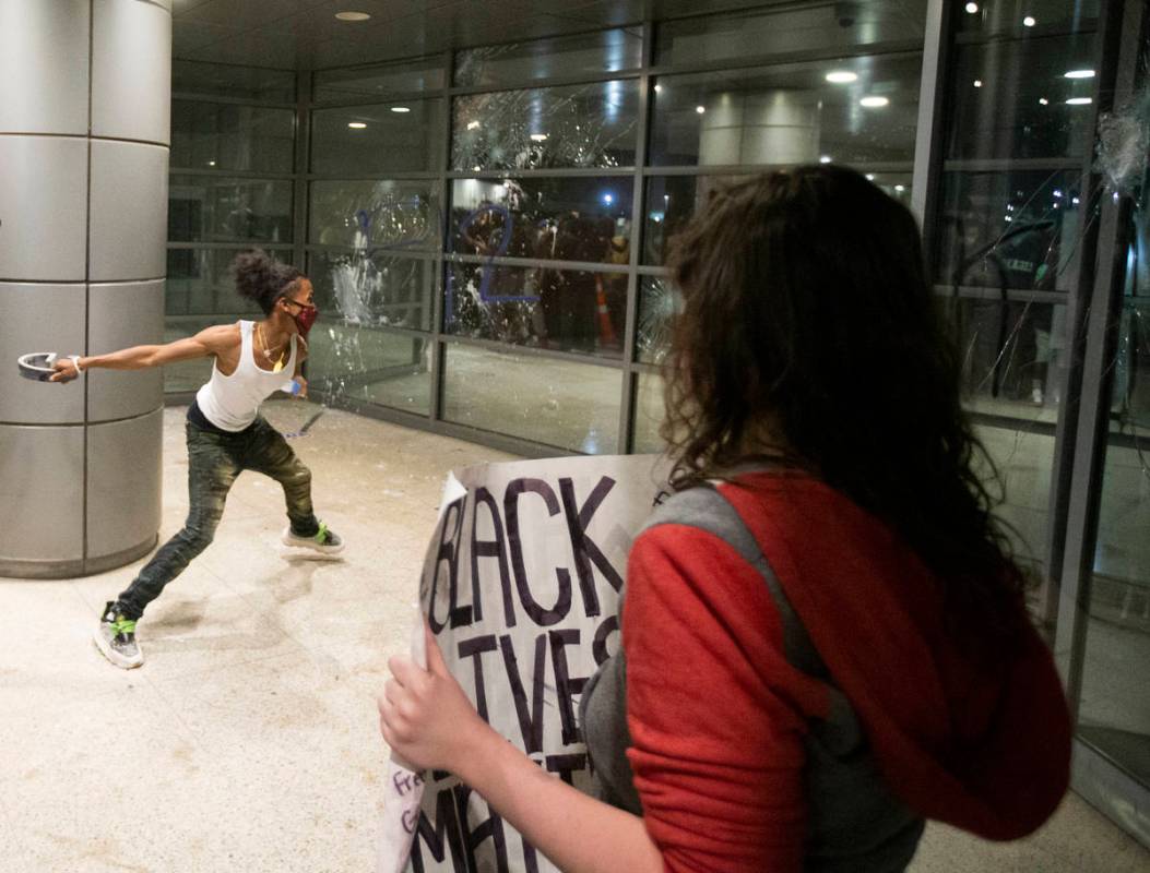 A protester throws a metal object at the window of an office building on South Las Vegas Boulev ...