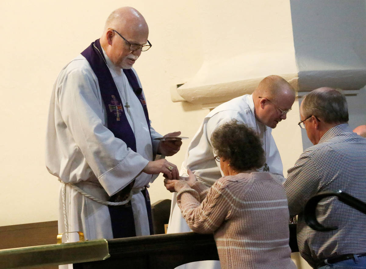 The Rev. J. Barry Vaughn, left and John Leslie Jr., a sub deacon, give the Holy Communion to fa ...
