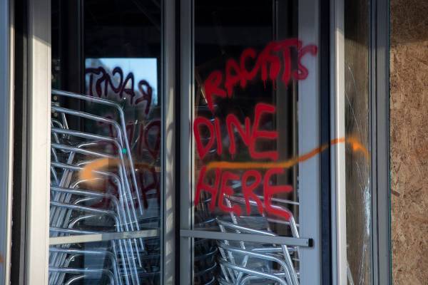 Spray paint the reads "Racists Dine Here" is seen on a revolving door or a restaurant ...