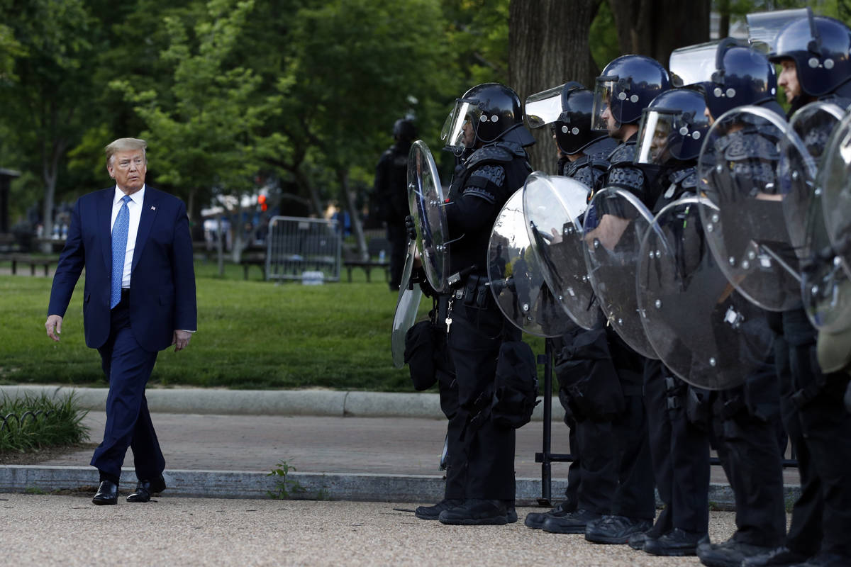 President Donald Trump walks past police in Lafayette Park after he visited outside St. John's ...