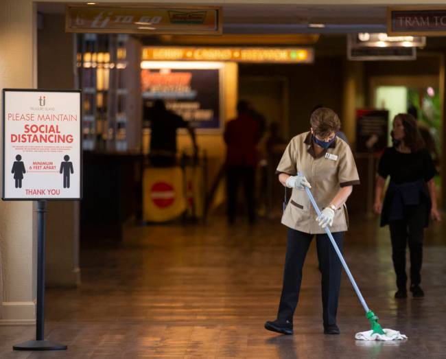 Housekeeping staff mop the floor next to a sign reinforcing social distancing at TI on Thursday ...
