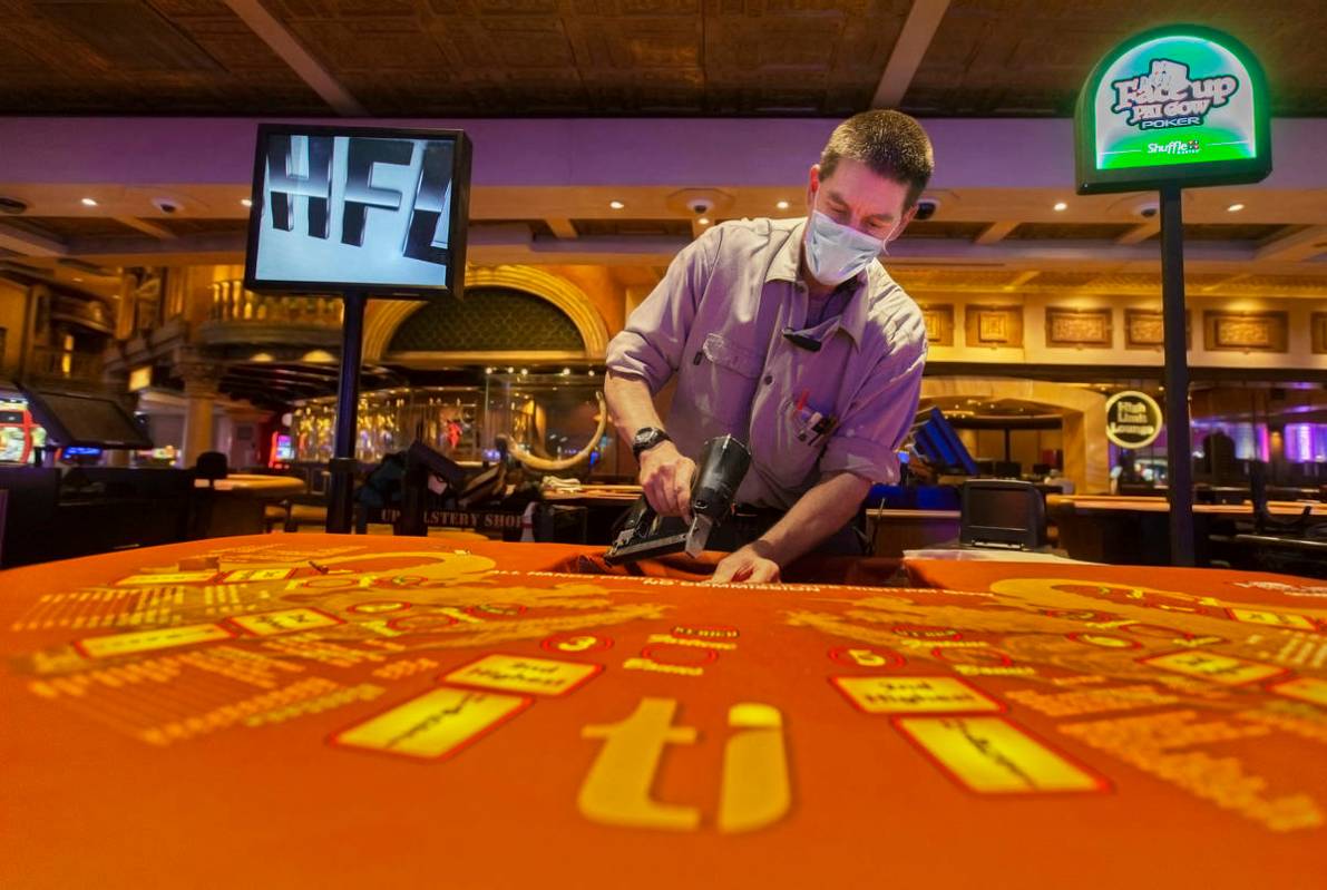 Facility technician Paul Burnett replaces the layouts on the Face Up Pai Gow poker tables on Mo ...