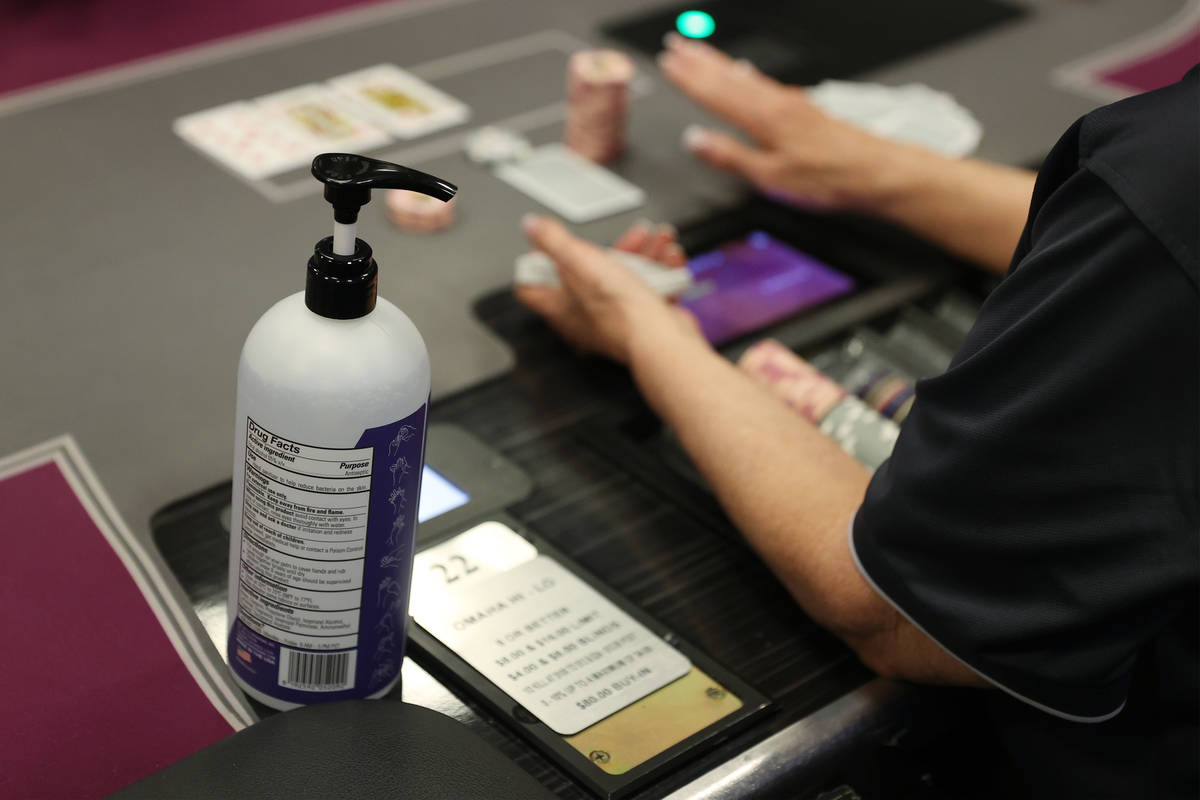 A hand sanitizer bottle sits on a poker tables during the first day of reopening at The Orleans ...