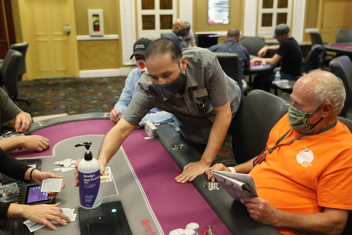 Poker shift manager Kenneth Davis deliver a new bottle of Gand sanitizer to a table in the poke ...