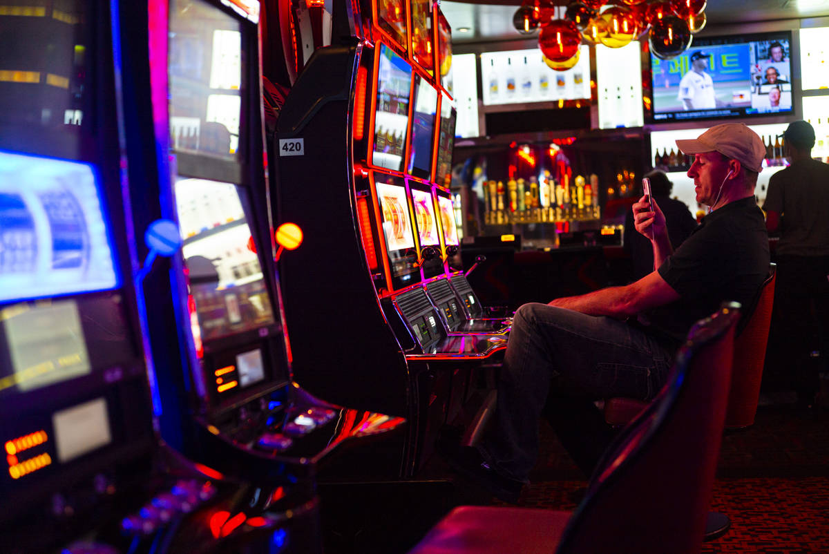A man records while playing slots at the Golden Nugget as hotel-casinos reopen in downtown Las ...