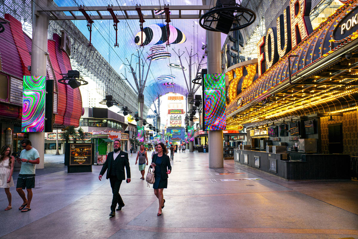 People walk around the Fremont Street Experience as hotel-casinos reopen in downtown Las Vegas ...