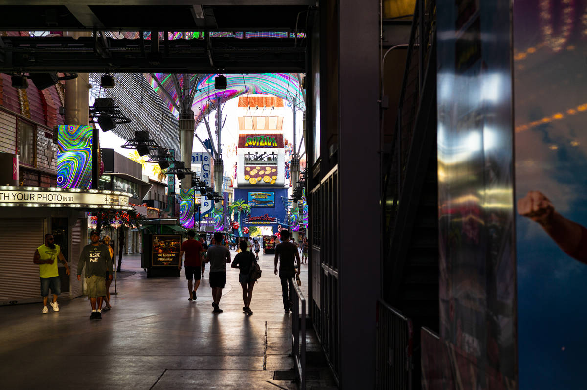 People walk around the Fremont Street Experience as hotel-casinos reopen in downtown Las Vegas ...